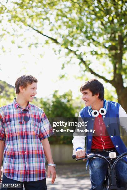 smiling teenage boys with bicycle - two boys talking stock-fotos und bilder