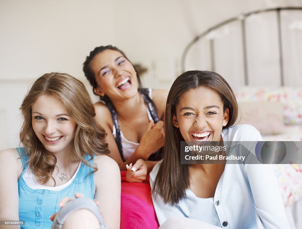 Smiling teenage girls laughing in bedroom