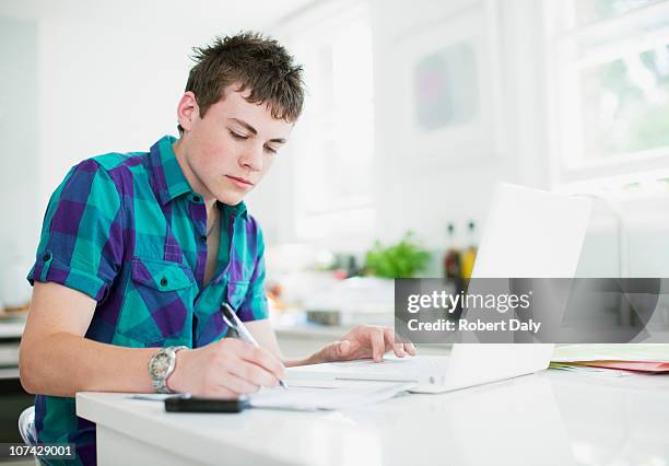 rapaz adolescente usando computador portátil e a fazer trabalho de casa - england imagens e fotografias de stock