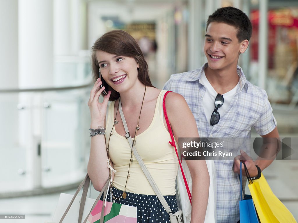 Teenage boy watching girlfriend talking on cell phone