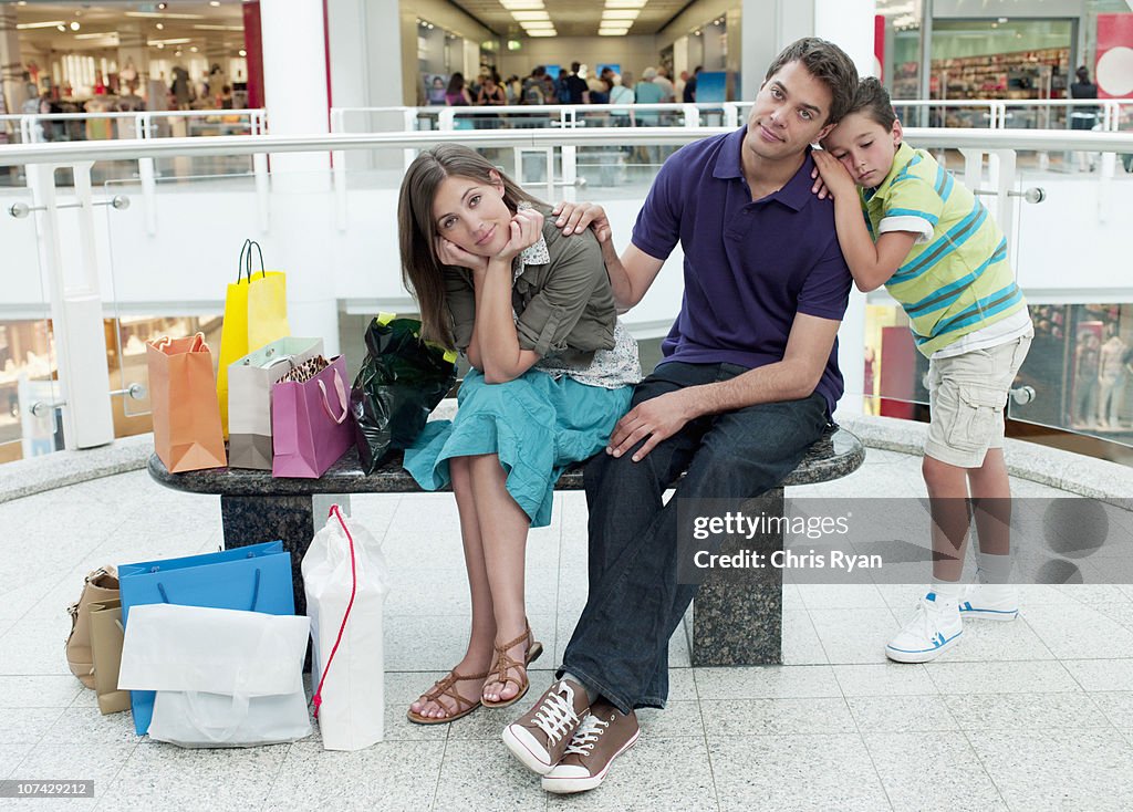 Smiling family in shopping mall relaxing on bench