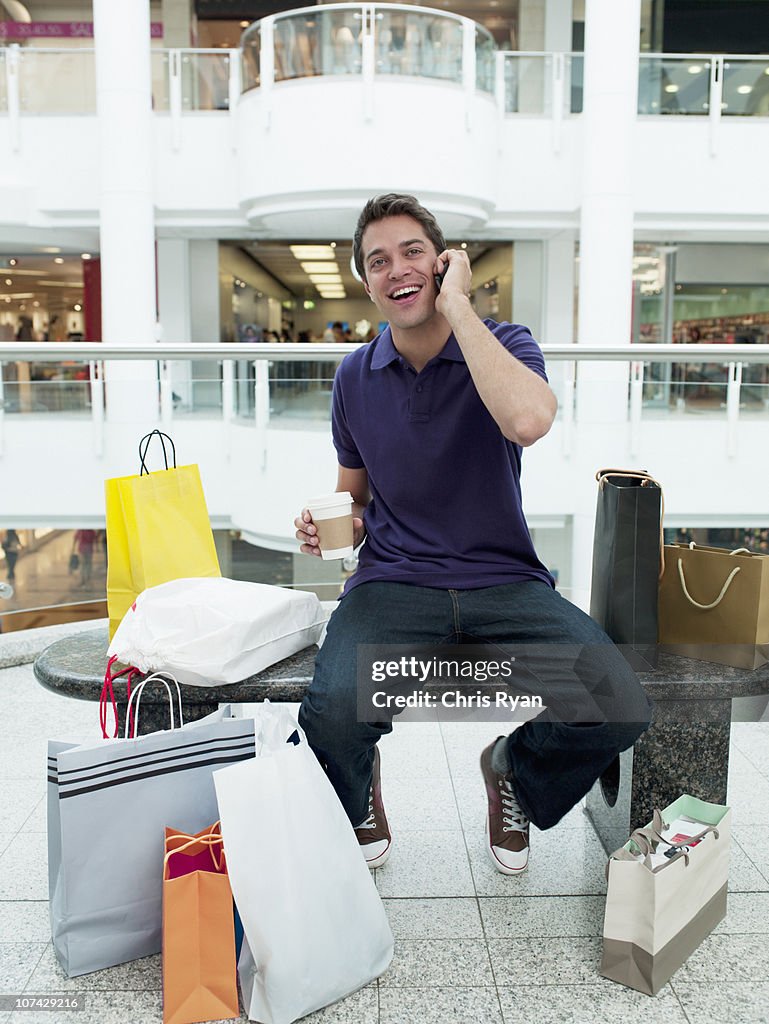 Homme souriant au centre commercial parler sur téléphone portable