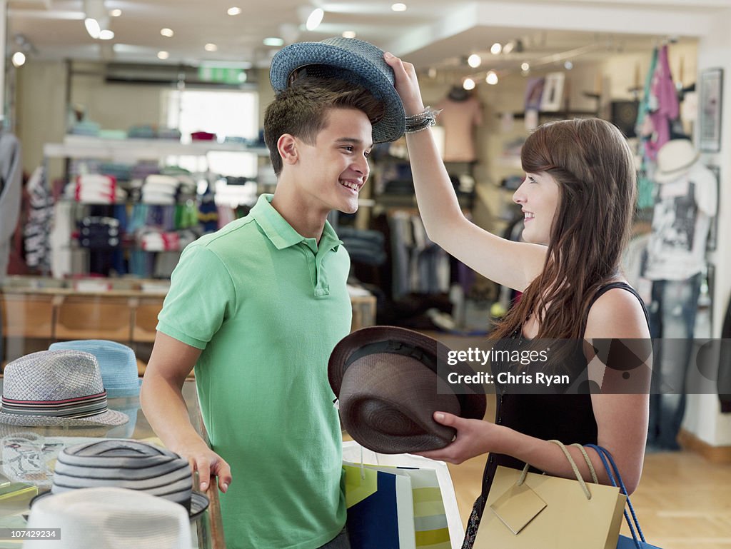 Smiling couple shopping for hats in store