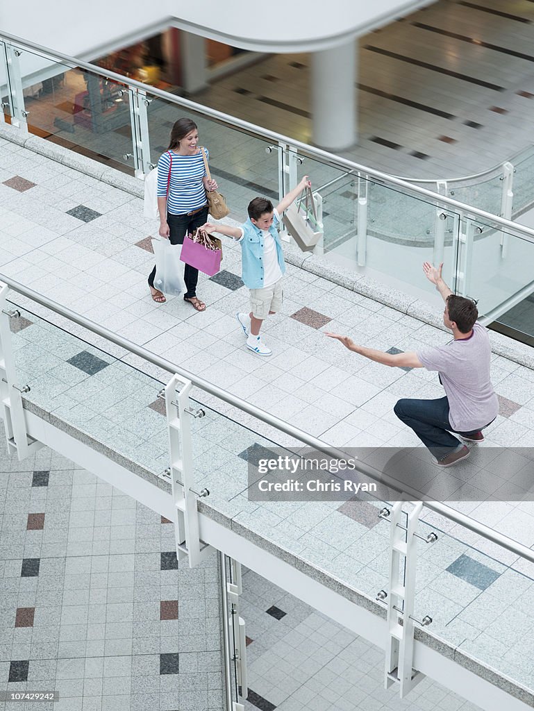 Son running towards father in shopping mall