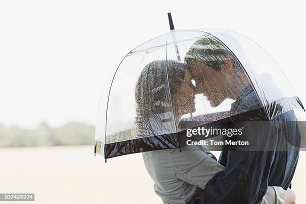 couple in rain hugging underneath umbrella - rain couple stockfoto's en -beelden