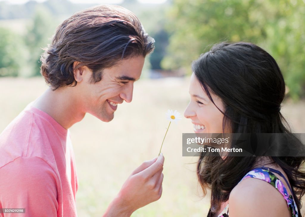 Smiling man giving wife daisy