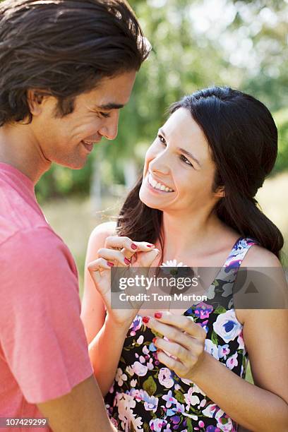 smiling couple plucking petals from daisy - tom chance stock pictures, royalty-free photos & images