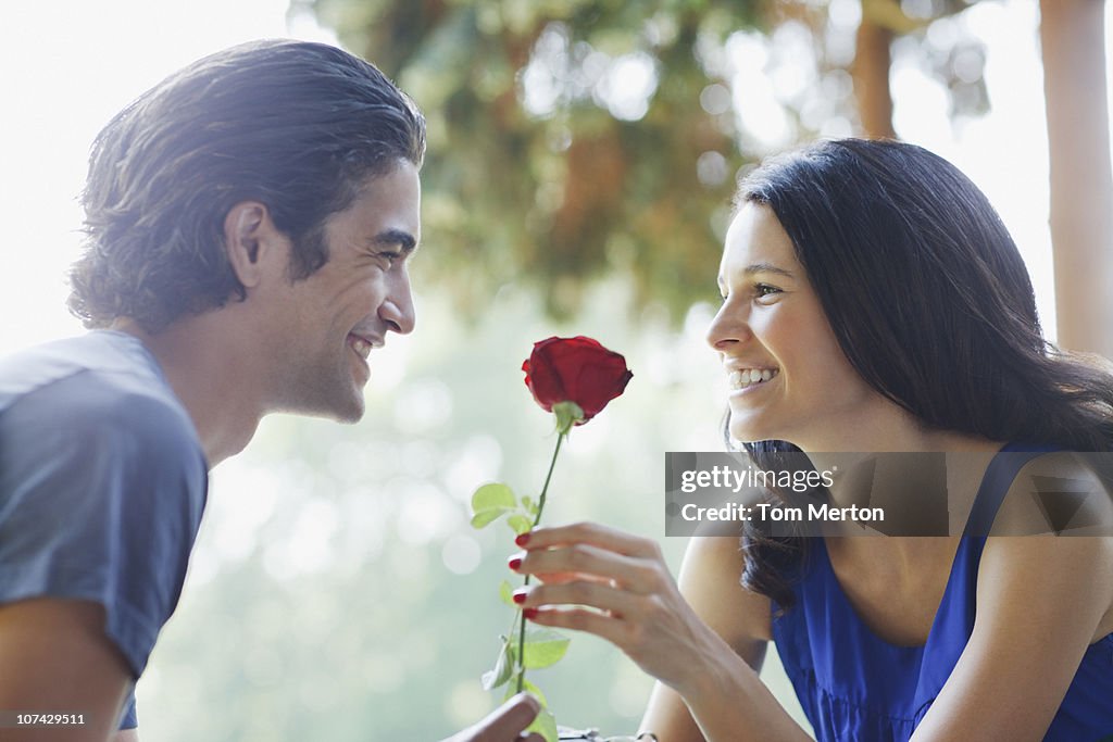 Smiling couple outdoors with red rose