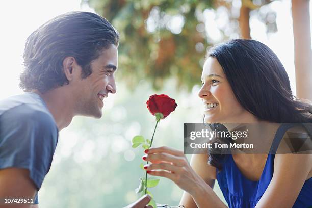 smiling couple outdoors with red rose - red grant stock pictures, royalty-free photos & images