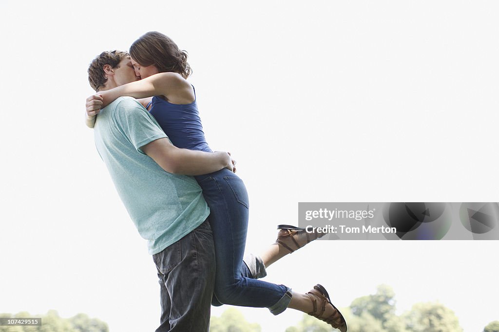 Homem a beijar e levantar esposa ao ar livre