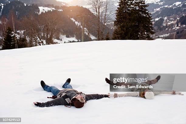couple making snow angels - holding hands in the snow stock pictures, royalty-free photos & images