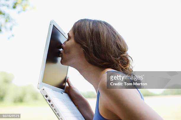 woman kissing laptop screen outdoors - obsessive woman stock pictures, royalty-free photos & images