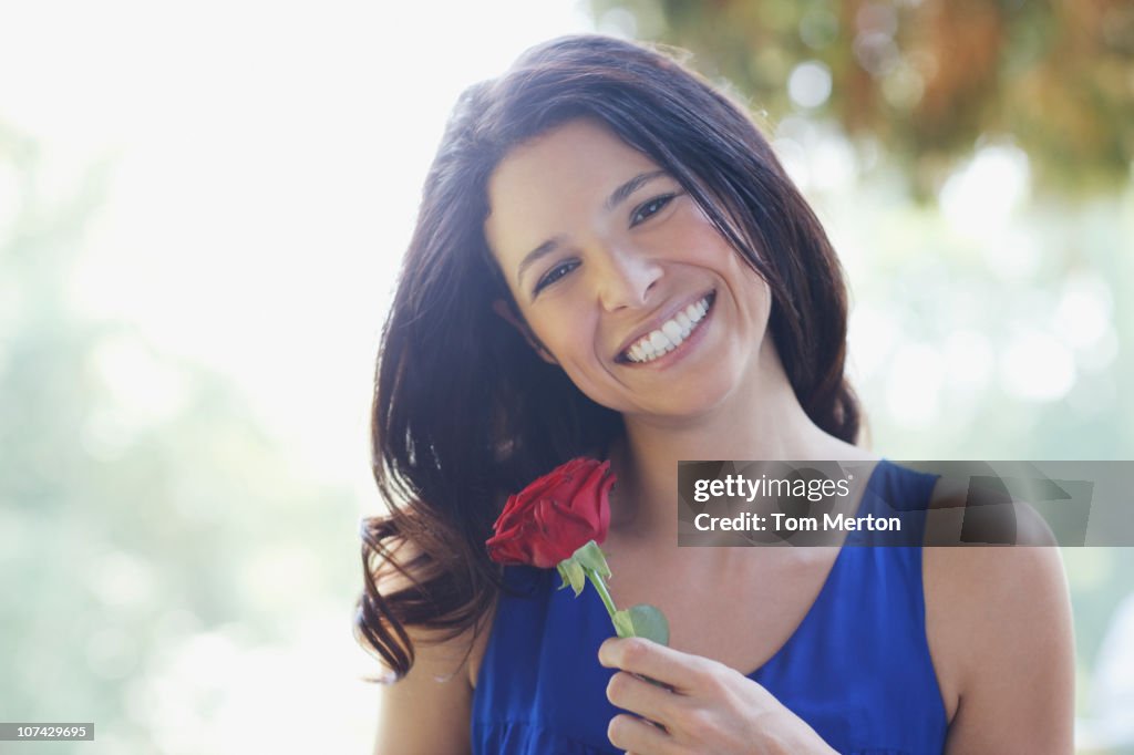 Smiling woman holding red rose