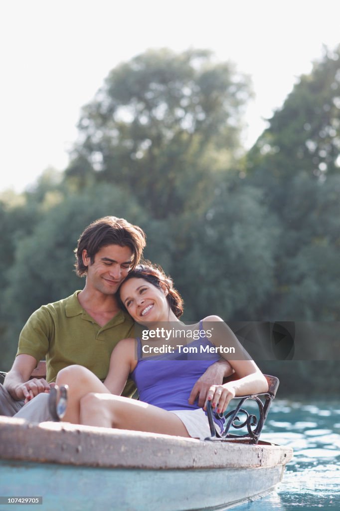 Smiling couple in rowboat on lake