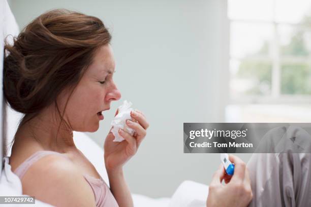 sick woman in bed blowing nose - illness stock pictures, royalty-free photos & images