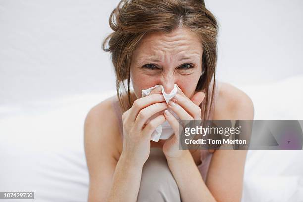 sick woman in bed blowing nose - snuit stockfoto's en -beelden