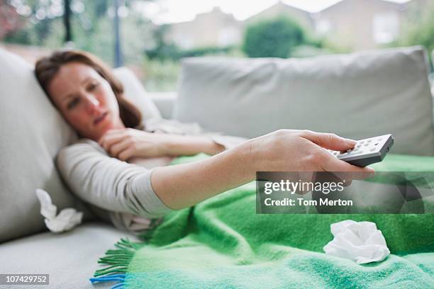 sick woman laying on sofa holding remote control - alter tv stock pictures, royalty-free photos & images