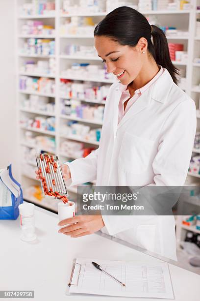 pharmacist in drug store measuring pills into bottle - pharmacist stock pictures, royalty-free photos & images