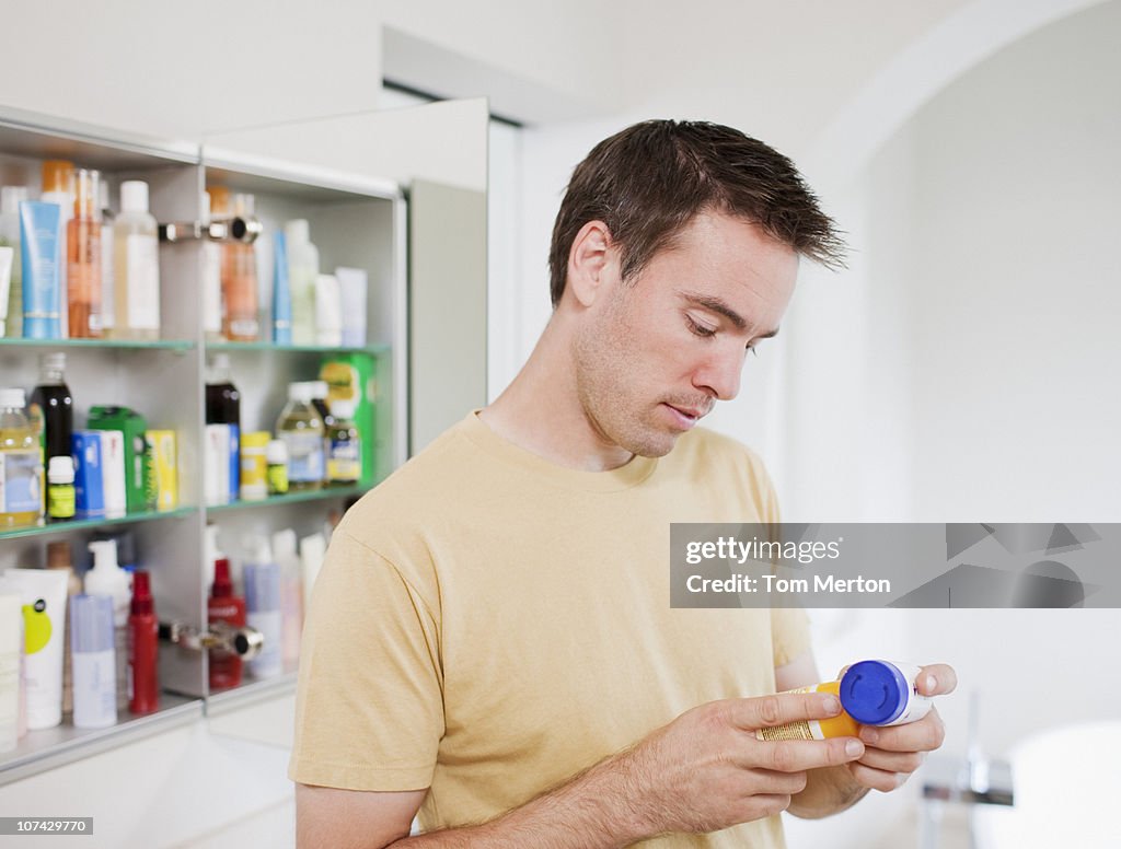 Man reading instructions on pill bottle