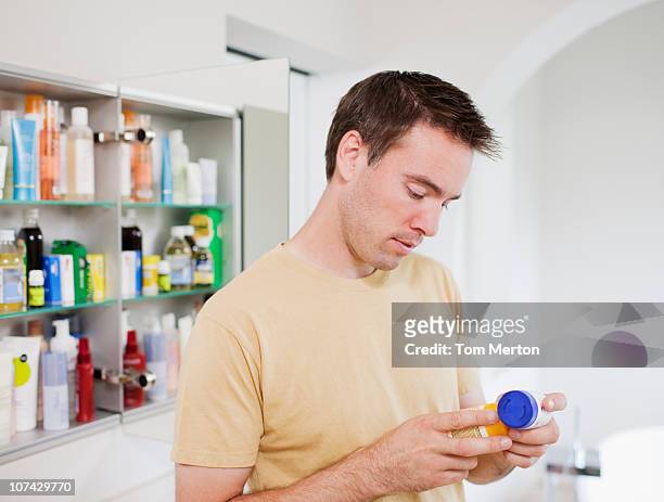 man reading instructions on pill bottle - bathroom medicine cabinet stock pictures, royalty-free photos & images
