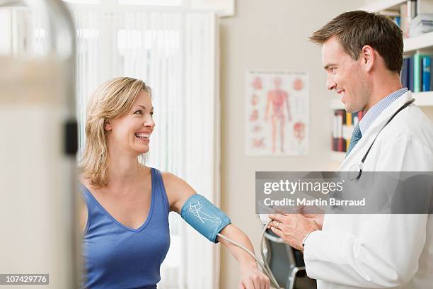 doctor taking patients blood pressure in doctors office - doctor side view stock pictures, royalty-free photos & images