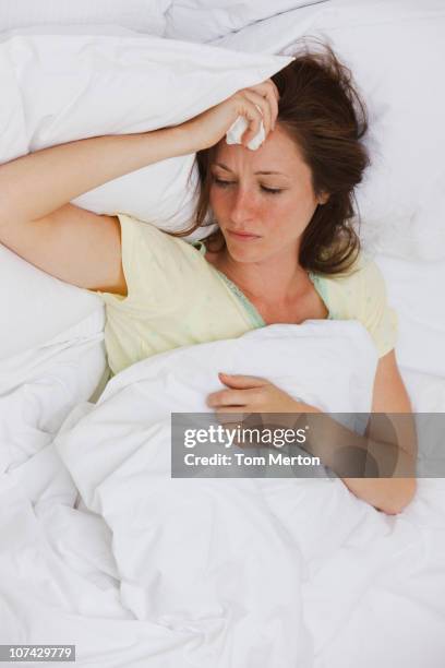 sick woman laying in bed - koorts stockfoto's en -beelden
