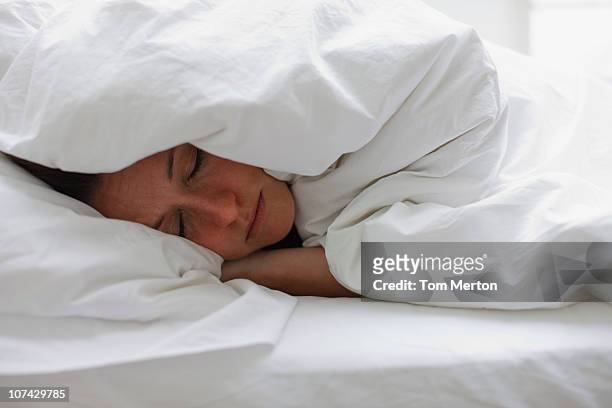 male donna che dorme nel letto sotto coperta - coprire foto e immagini stock