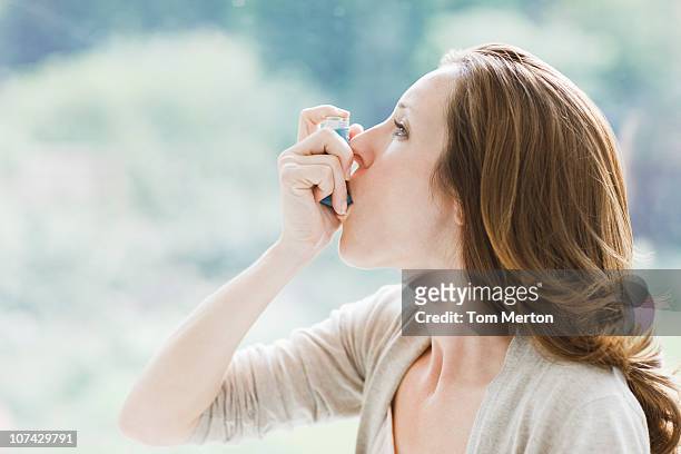 woman using asthma inhaler - asthma stockfoto's en -beelden
