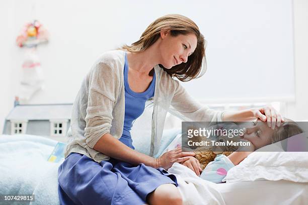 mother checking on sick daughter laying in bed - illness stock pictures, royalty-free photos & images