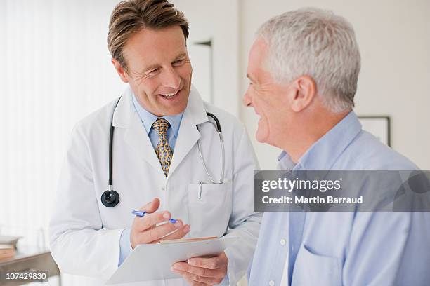 doctor talking with patient in doctors office - senior men talking stock pictures, royalty-free photos & images