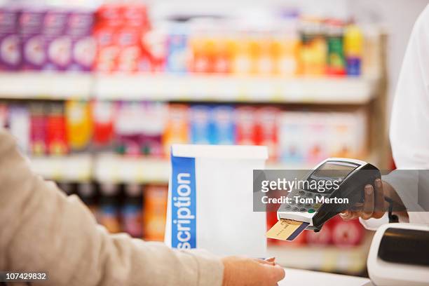 pharmacist holding security device for customer in drug store - security_(finance) bildbanksfoton och bilder