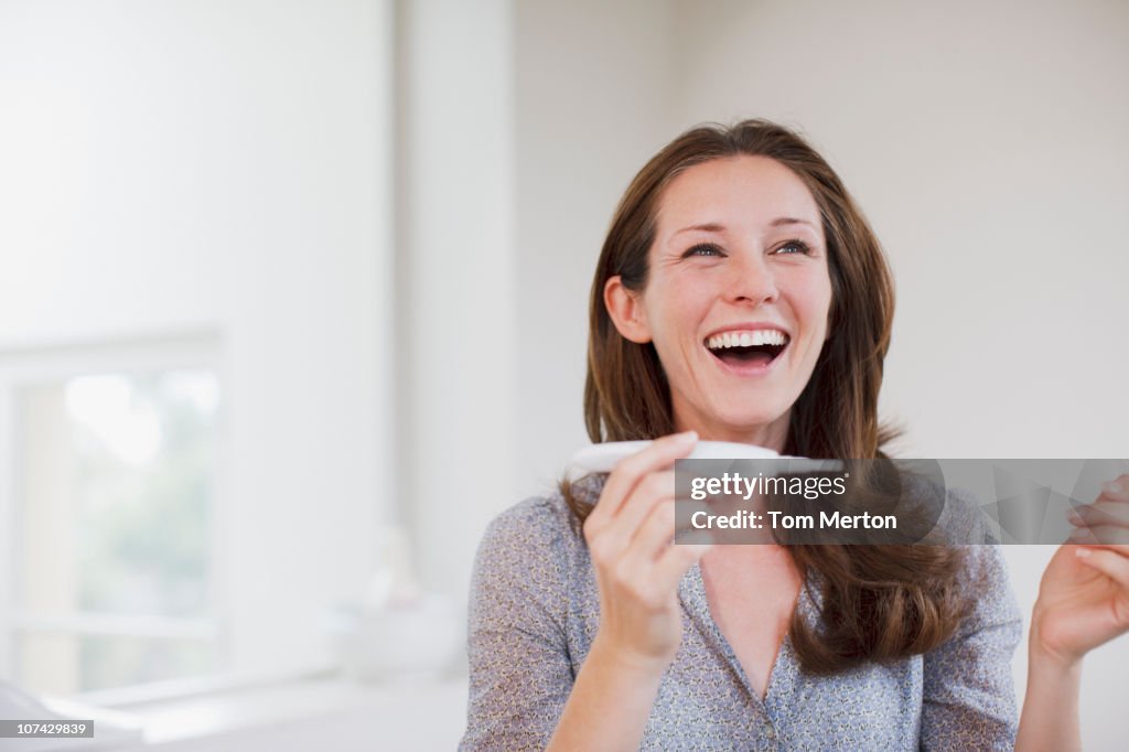 Happy woman holding pregnancy test