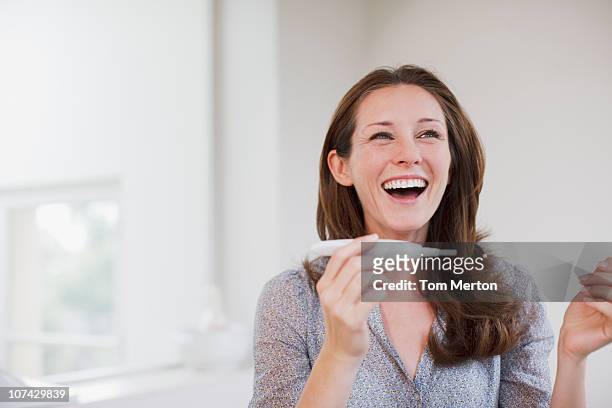 happy woman holding pregnancy test - family planning stock pictures, royalty-free photos & images