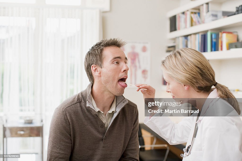 Doctor examining patients throat in doctors office