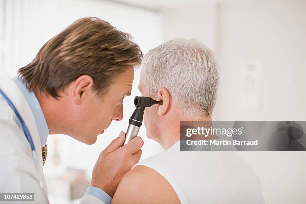 doctor examining patients ear in doctors office - human ear stockfoto's en -beelden