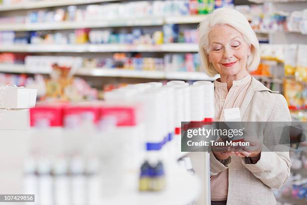 senior woman reading package in drug store - pharmacy customer stock pictures, royalty-free photos & images