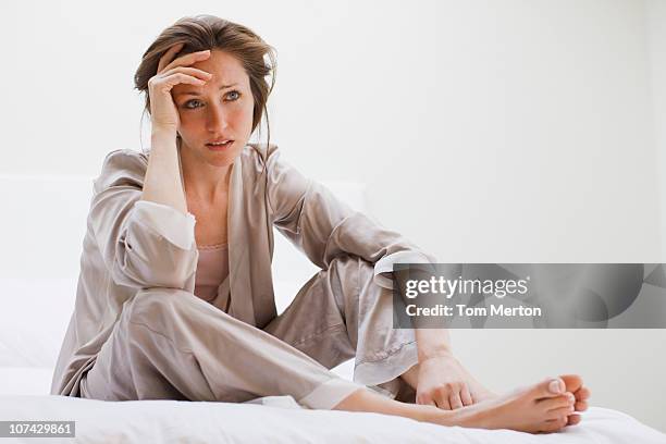 depressed woman in pajamas sitting in bed - fatigue full body stock pictures, royalty-free photos & images