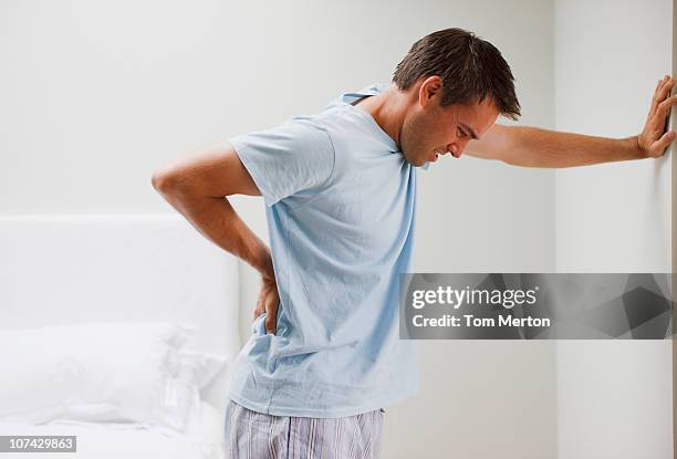hombre con dolor de espalda fuertemente contra la pared - back pain fotografías e imágenes de stock