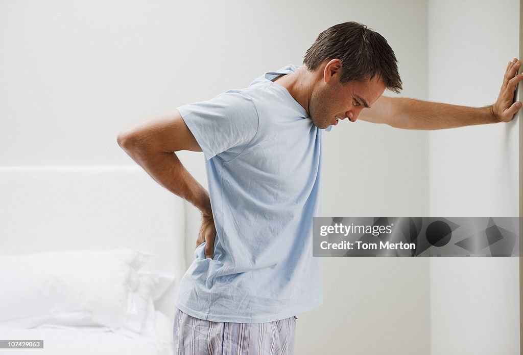 Man with backache leaning against wall