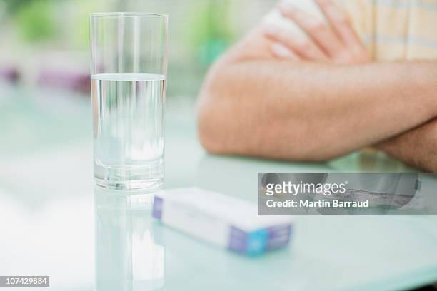 man sitting with glass of water and box of pills - vitamin sachet stock pictures, royalty-free photos & images