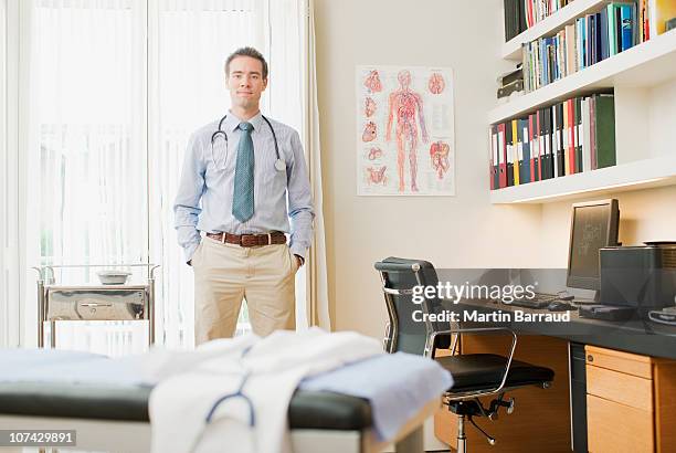 doctor standing in doctors office - tentamenzaal stockfoto's en -beelden