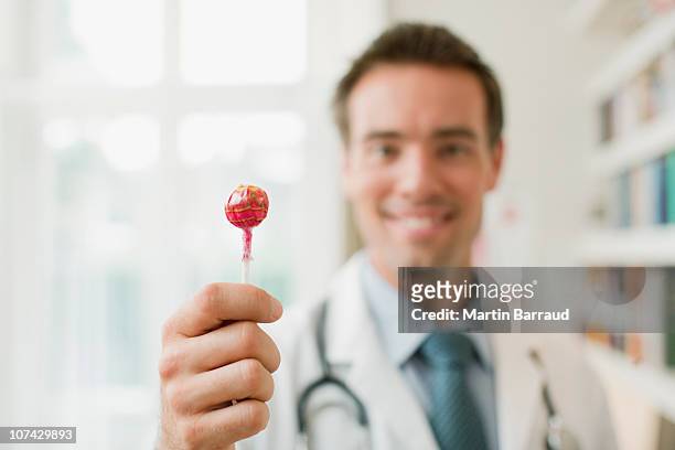 doctor holding a cabo piruleta en la oficina de médicos - lollipop fotografías e imágenes de stock