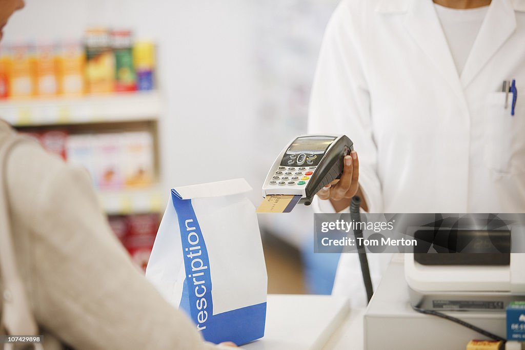 Pharmacist holding security device for customer in drug store