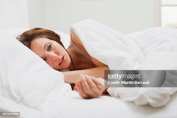 sick colocación de mujer en la cama con edredón de plumas - fever fotografías e imágenes de stock