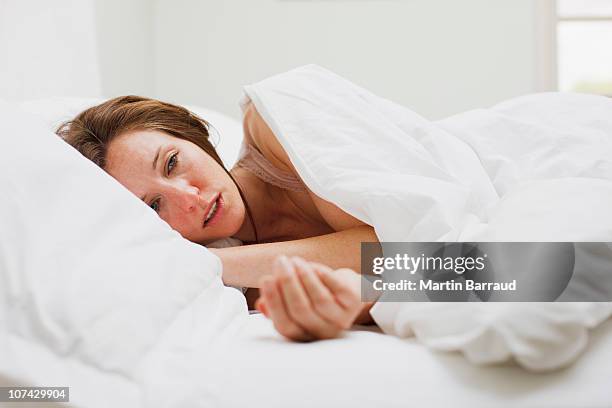 sick woman laying in bed under blanket - body temperature stock pictures, royalty-free photos & images