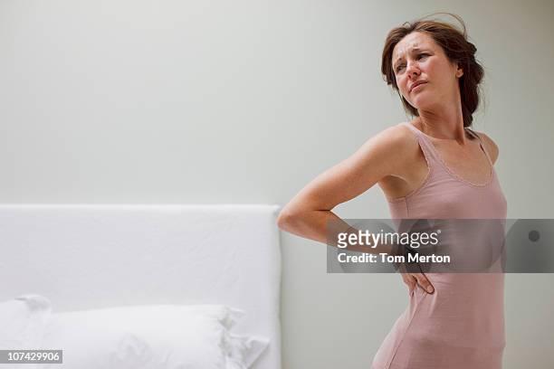frau reiben rückenschmerzen im schlafzimmer - back pain bed stock-fotos und bilder