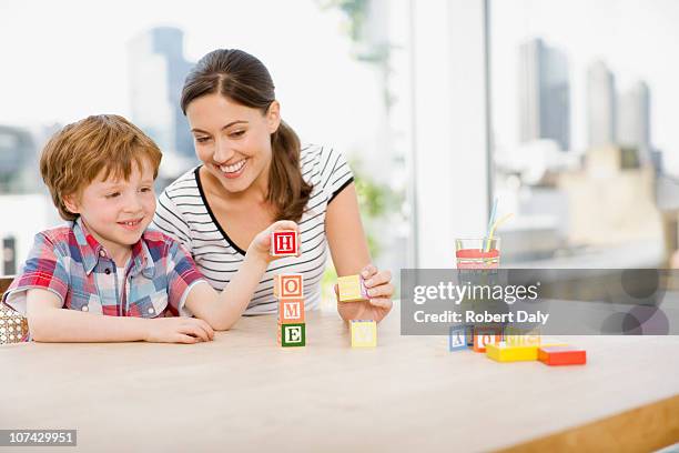 mother watching son stacking alphabet blocks and spelling home - child and blocks stock pictures, royalty-free photos & images