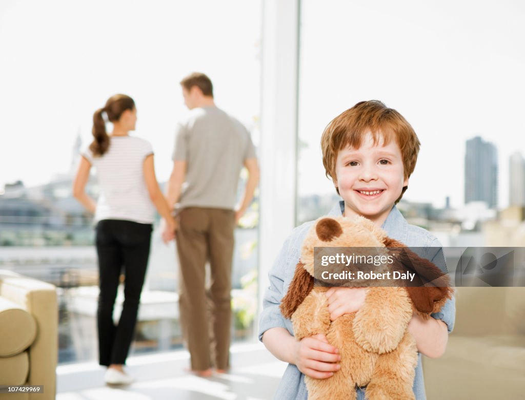 Boy holding stuffed dog with parents in background