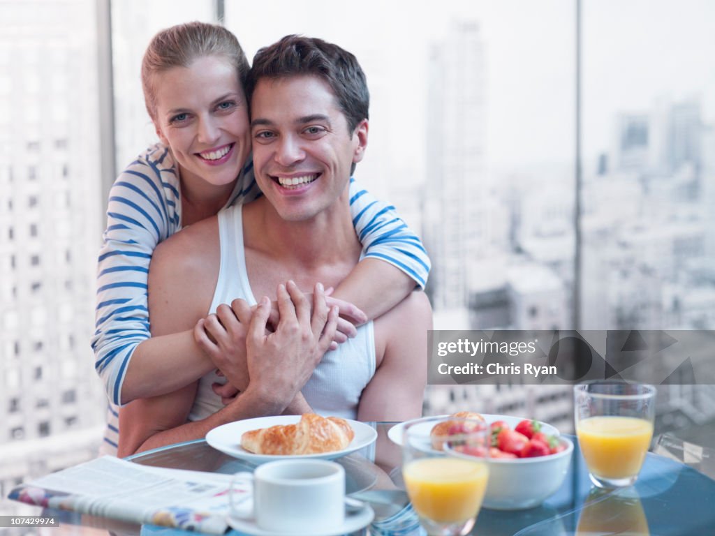 Couple hugging with breakfast on the table