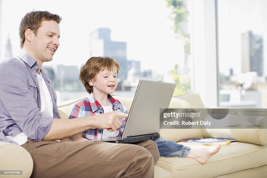 Père et fils à l'aide d'un ordinateur portable dans la salle de séjour